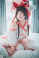 A woman in a red and white outfit sitting on a bed.