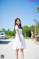 A woman in a white dress standing on a road.