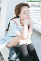 A woman in a school uniform sitting on a ledge.