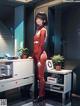 A woman in a red suit standing in front of a computer.