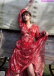 A woman in a red dress standing next to a wagon.