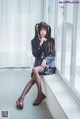 A woman in a school uniform sitting on a window sill.