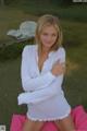 A woman in a white shirt sitting on a pink pillow.