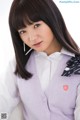 A young woman wearing a purple vest and a white shirt.