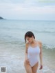 A woman in a white bathing suit standing on the beach.